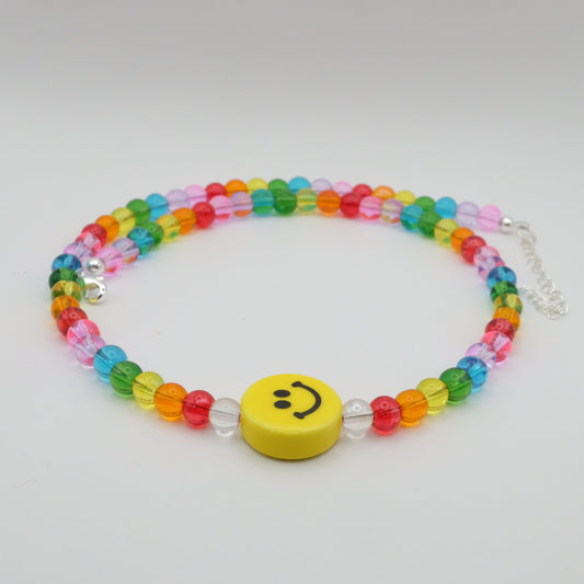 Colorful beaded necklace with a smiley face charm on a light gray background