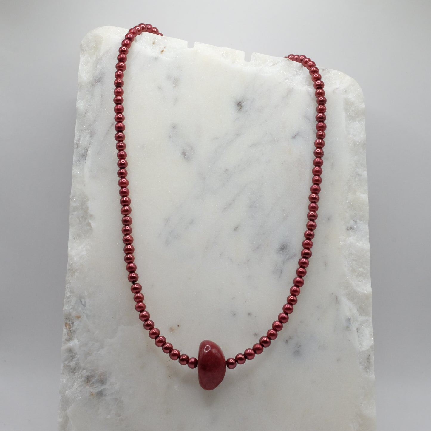Red beaded necklace on a marble surface