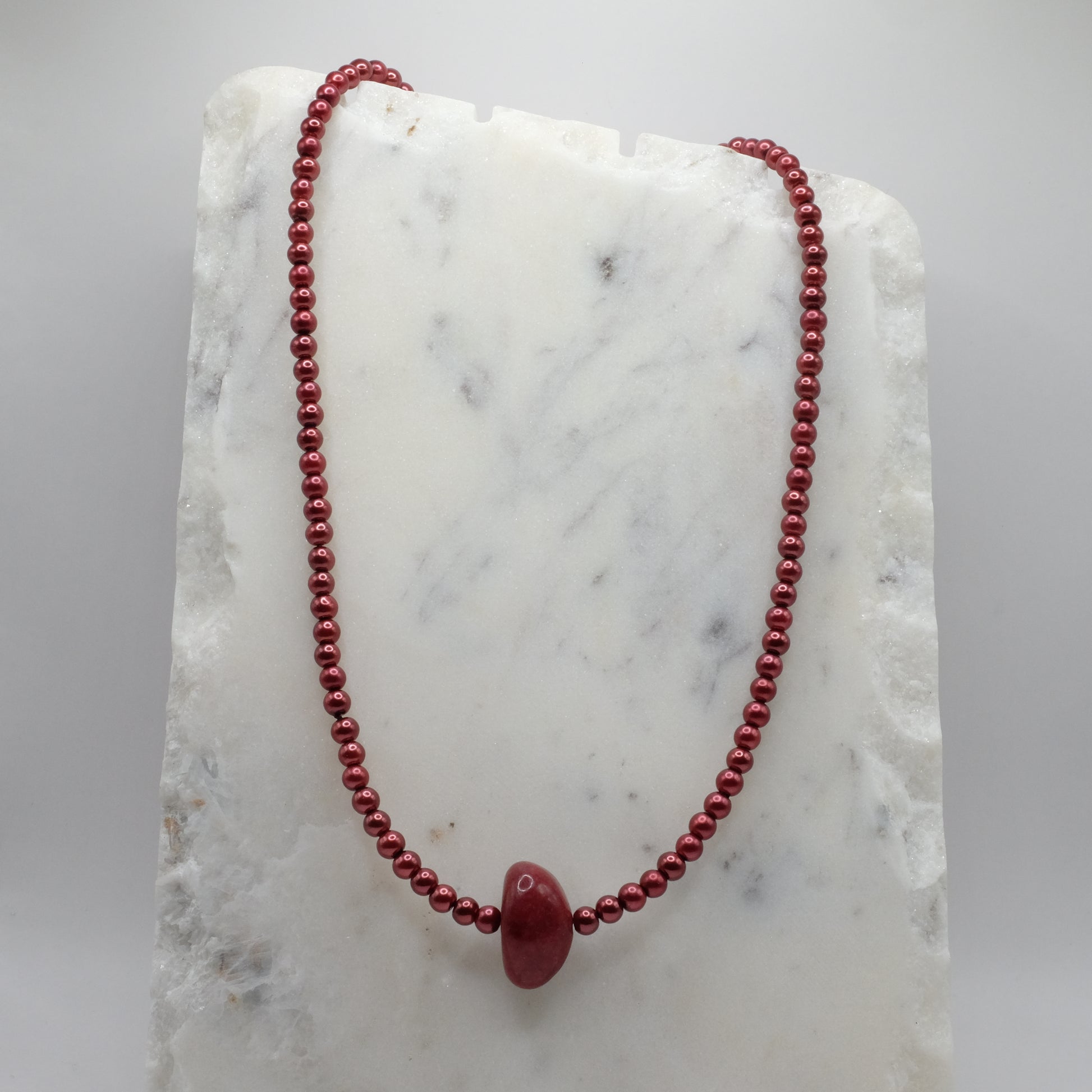 Red beaded necklace on a marble surface