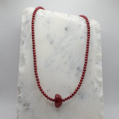 Red beaded necklace on a marble surface
