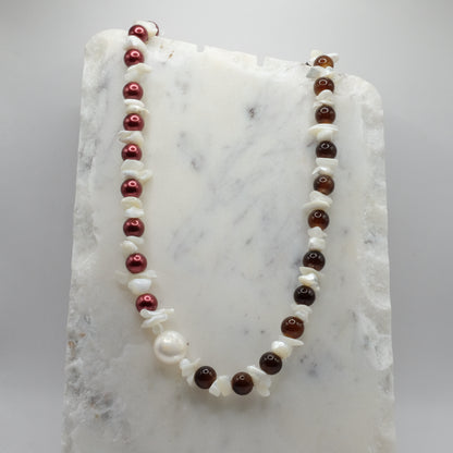 Necklace with red, brown, and white beads on a marble surface