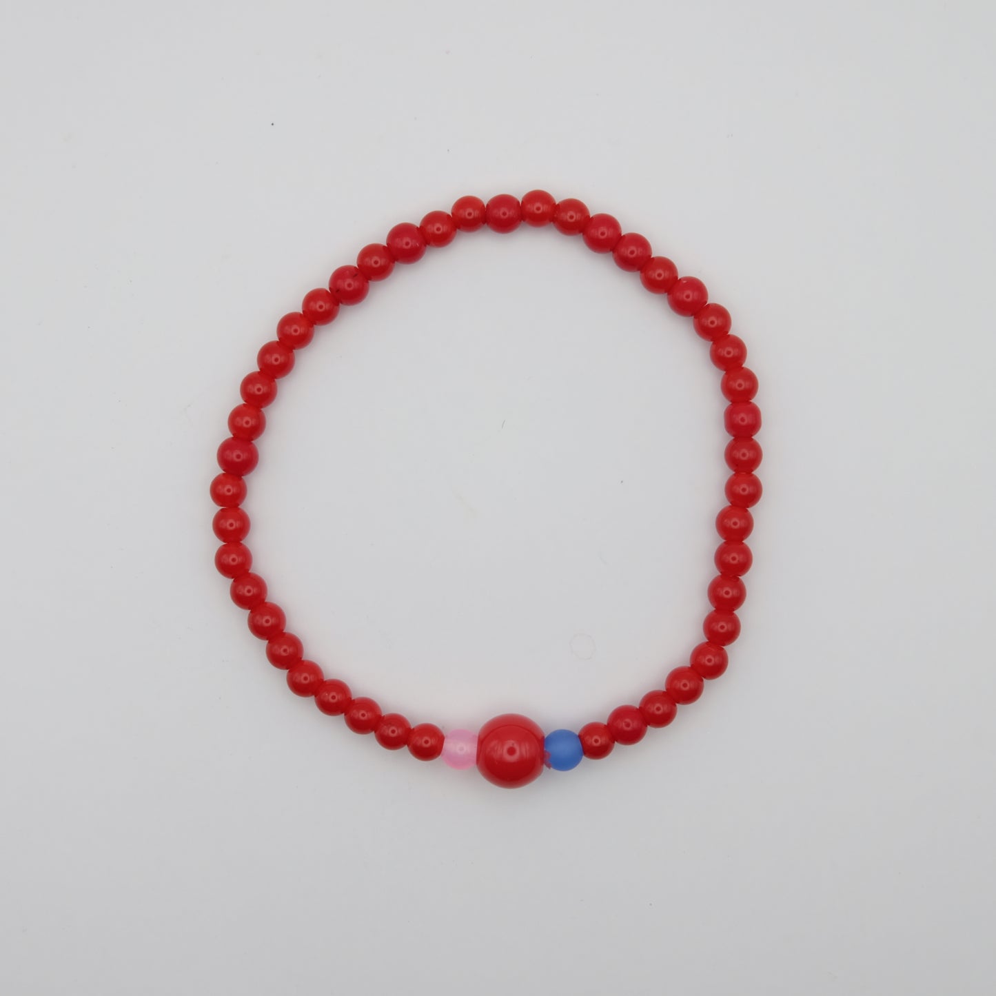 Red beaded bracelet with pink and blue accents on a white background