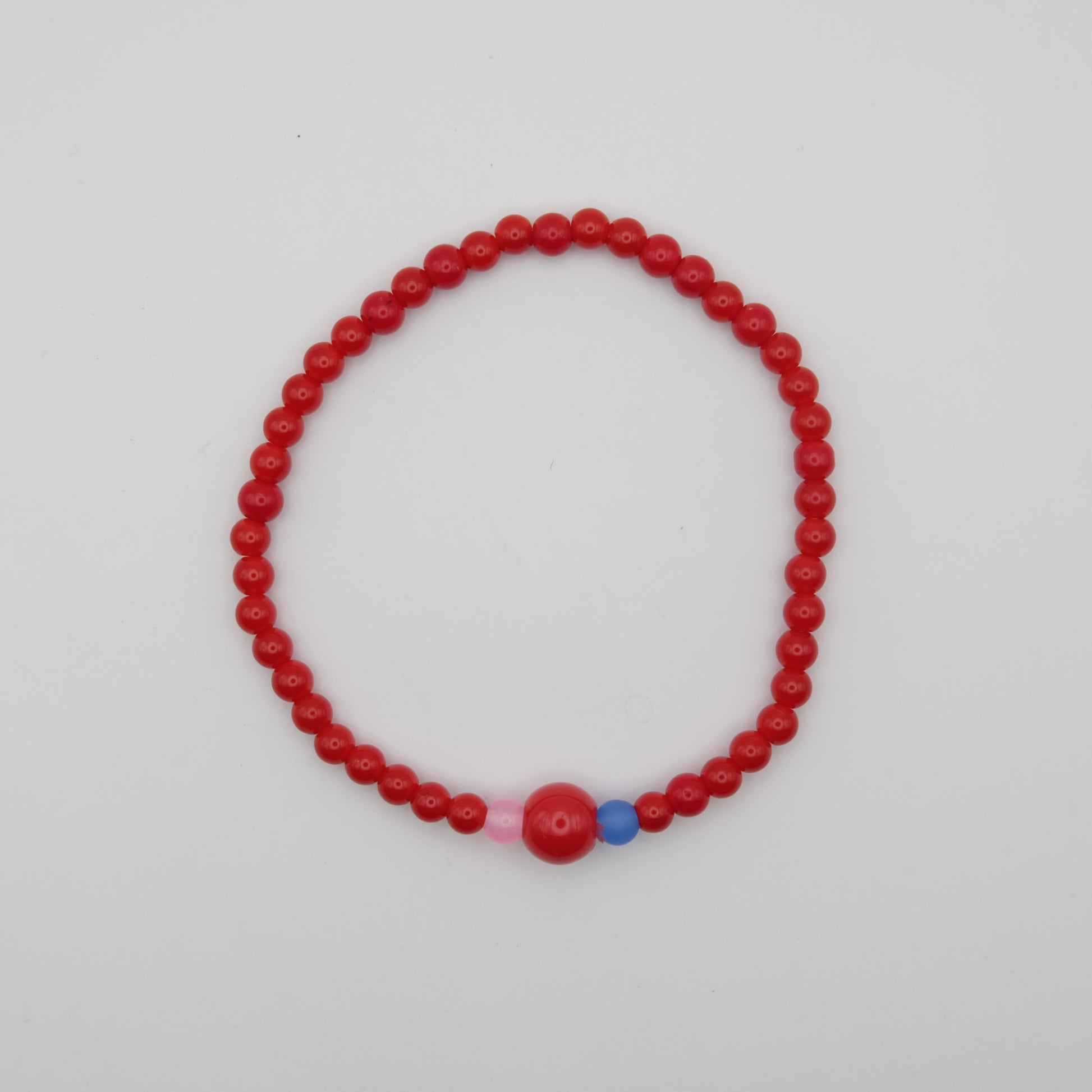 Red beaded bracelet with pink and blue accents on a white background