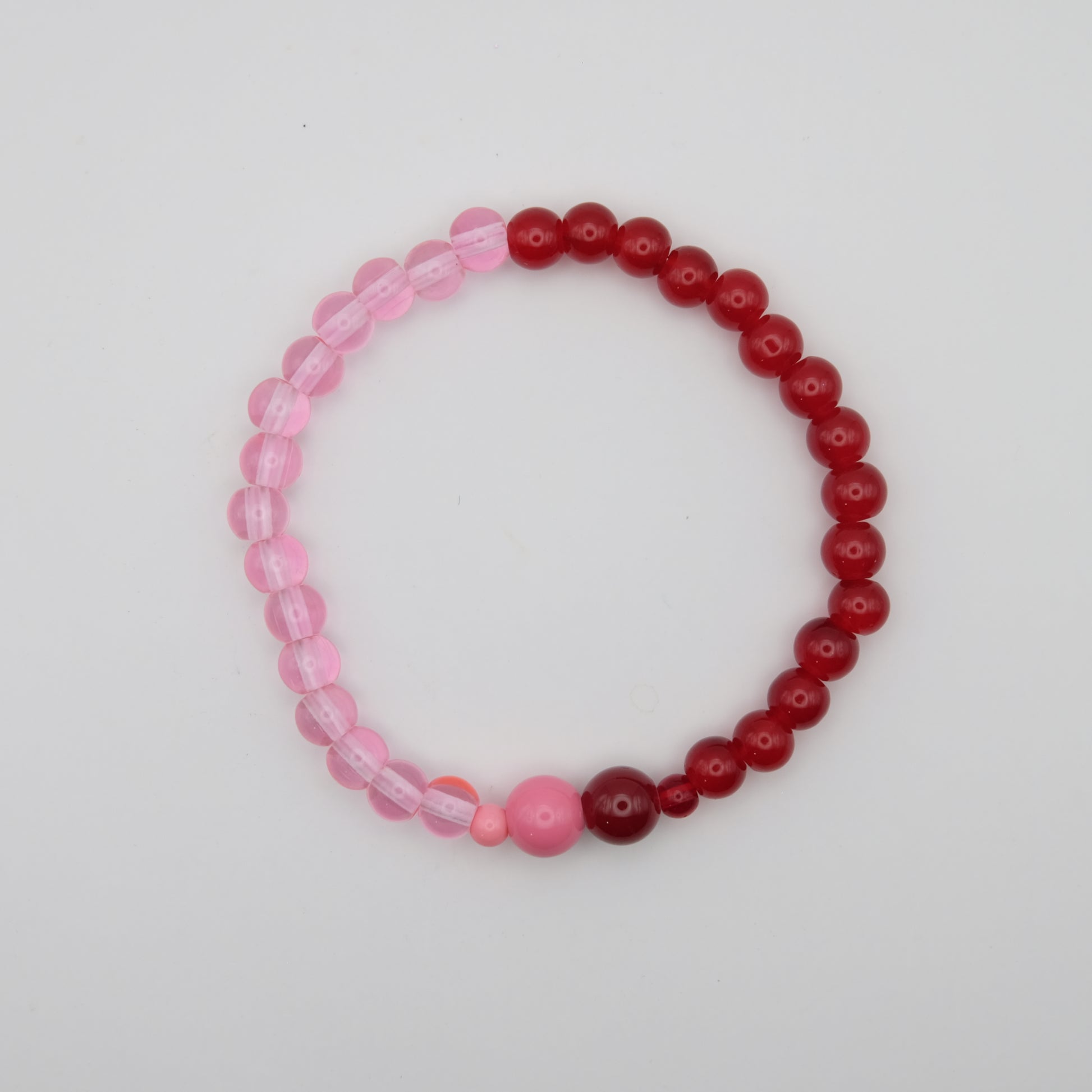 Beaded bracelet with pink and red beads on a light gray background