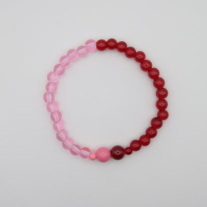 Beaded bracelet with pink and red beads on a light gray background