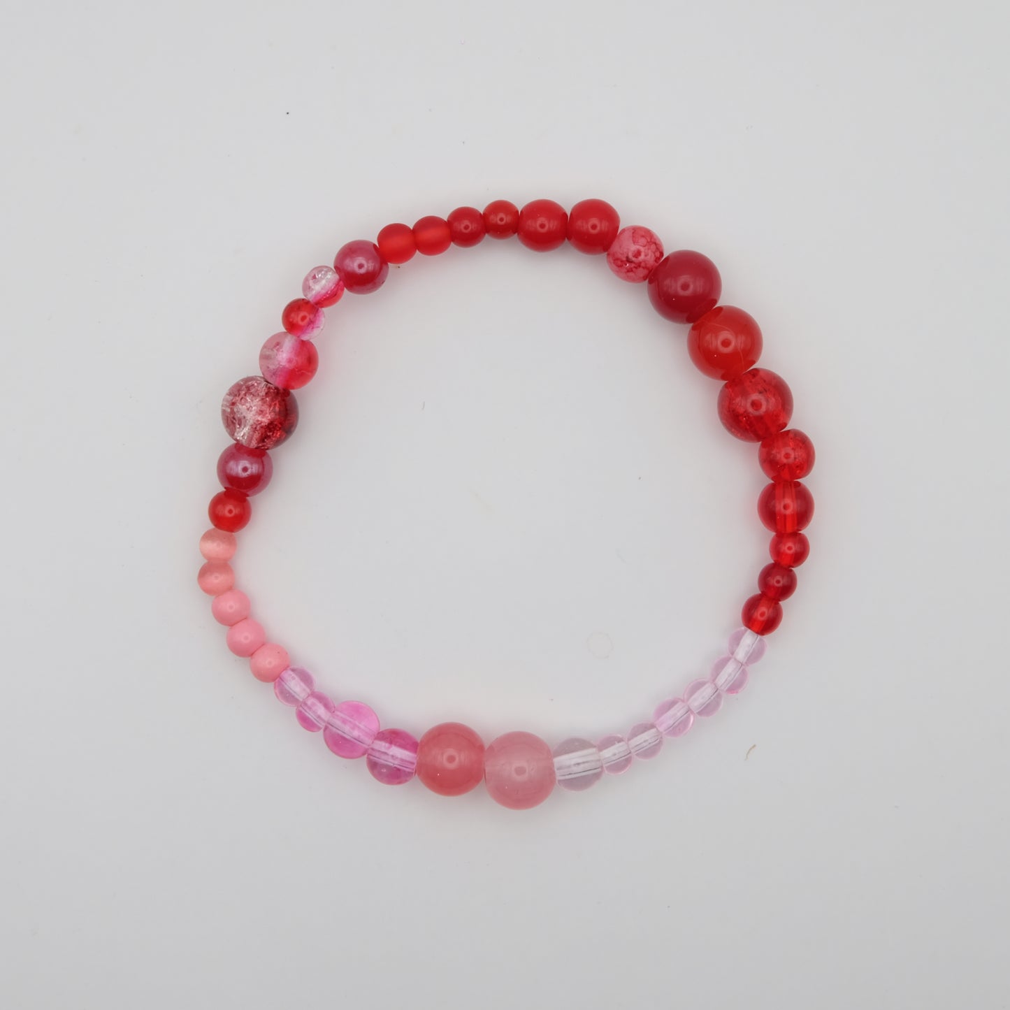 Beaded bracelet with red and pink beads on a white background