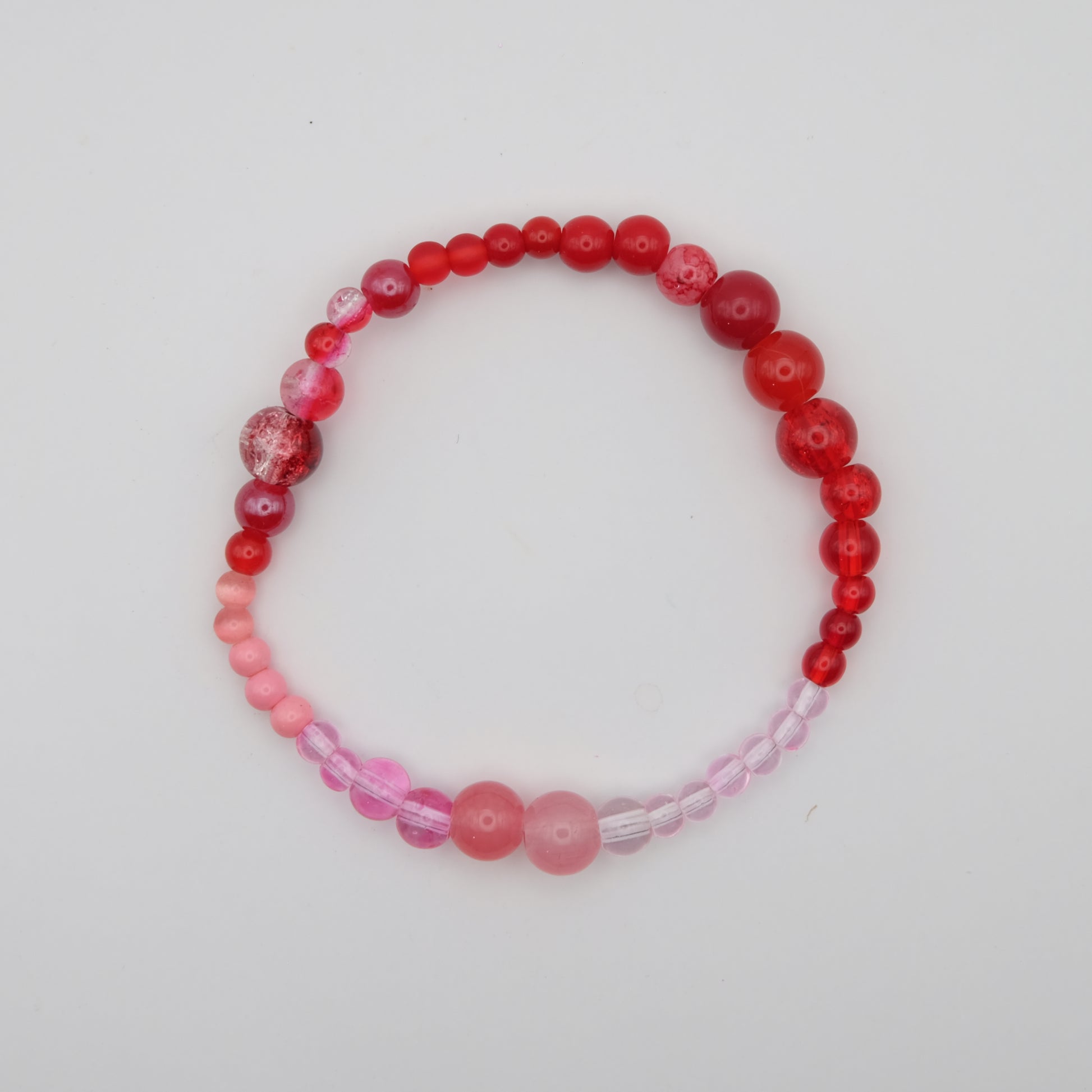 Beaded bracelet with red and pink beads on a white background