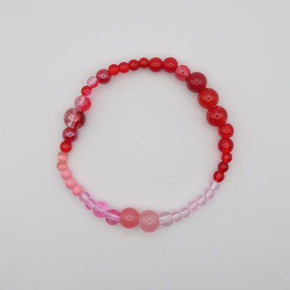 Beaded bracelet with red and pink beads on a white background
