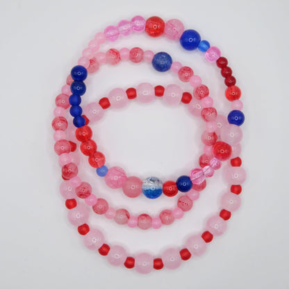 Set of 3beaded bracelets in pinks, blues and reds on a white background