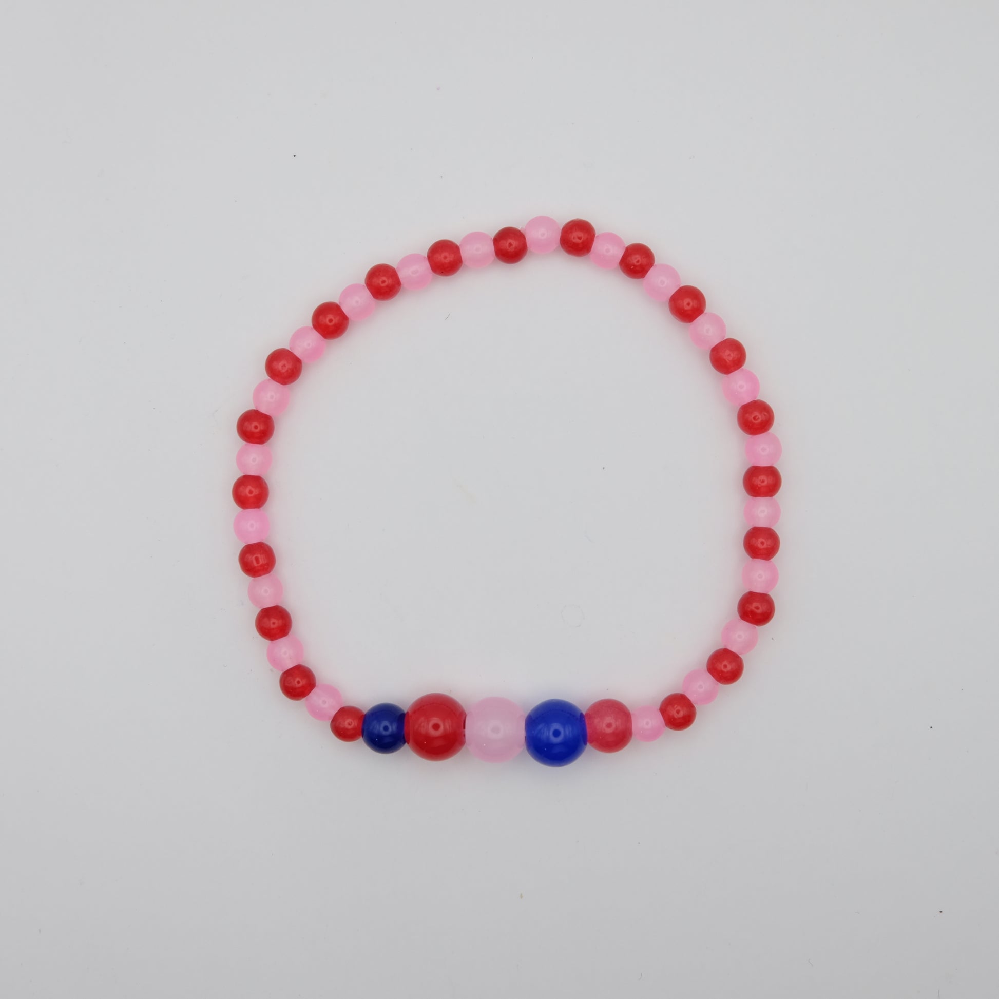 Beaded bracelet with pink, red, and blue beads on a light gray background