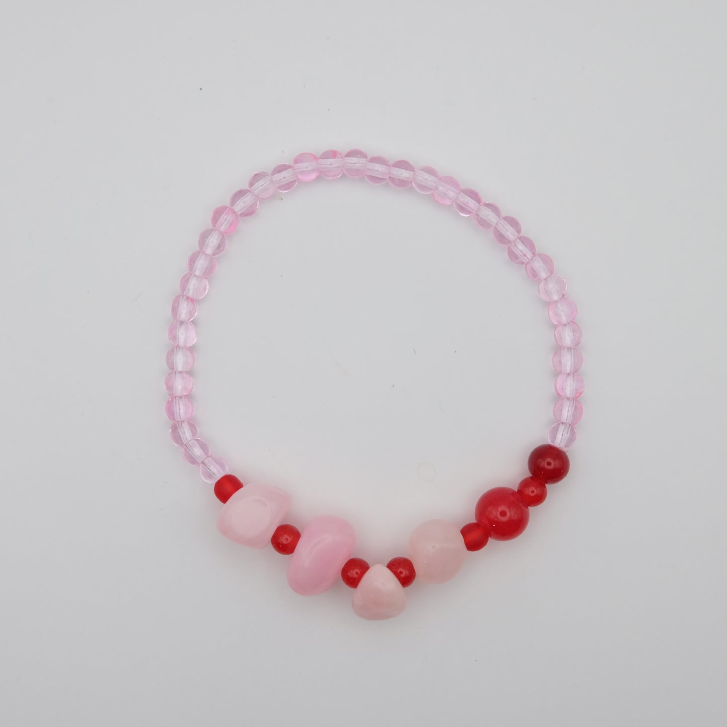 Beaded bracelet with pink and red beads on a light gray background