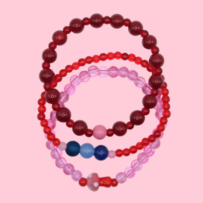 A handmade one of a kind bracelet stack made from 4mm to 8mm glass beads in vibrant pink, red and blue tones, styled together.