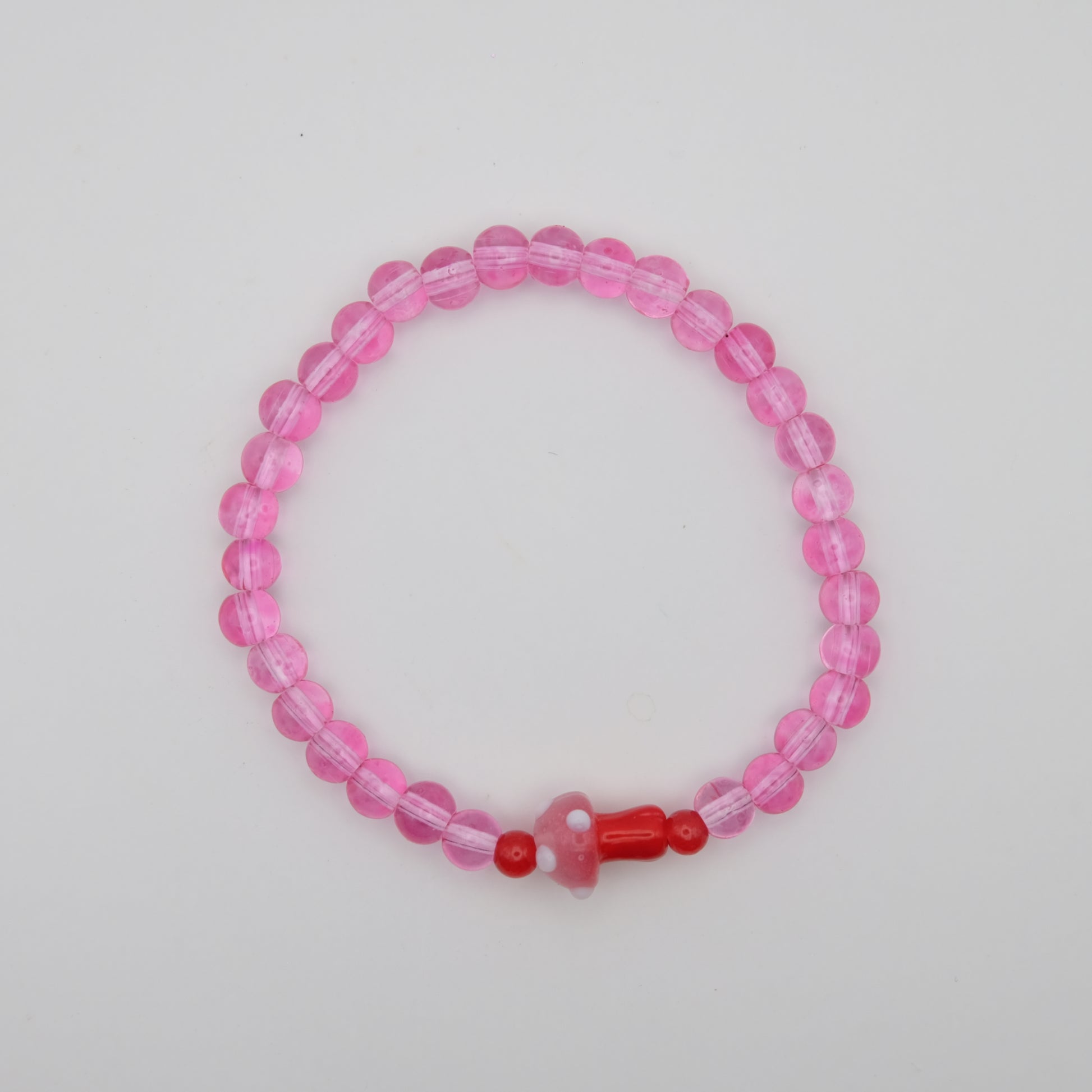 Pink beaded bracelet with a red accent on a plain background