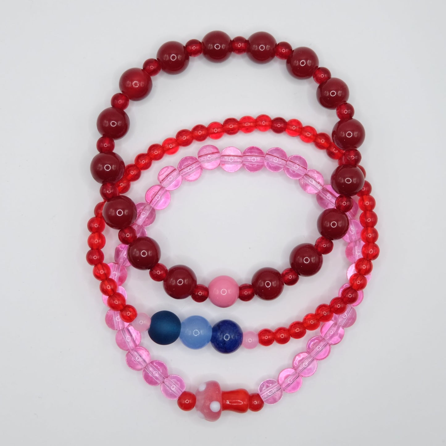 Stack of red and pink beaded bracelets on a light gray background