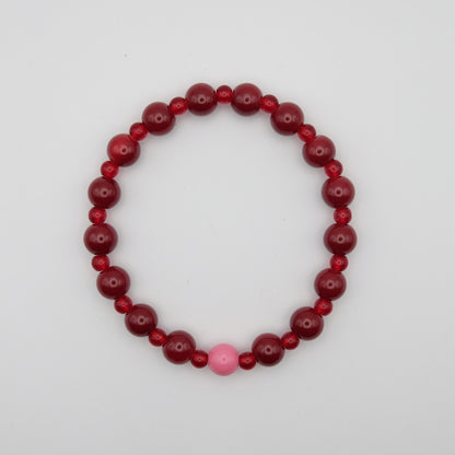Beaded bracelet with red and pink beads on a plain background