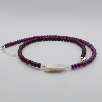 Purple beaded bracelet with a clear crystal bead on a light gray background
