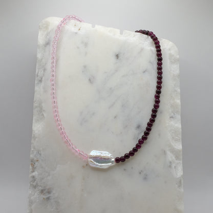 Beaded necklace with pink and red beads on a marble surface