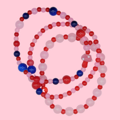 Beaded bracelet stack of 3 with pink, red, and blue beads on a pink background