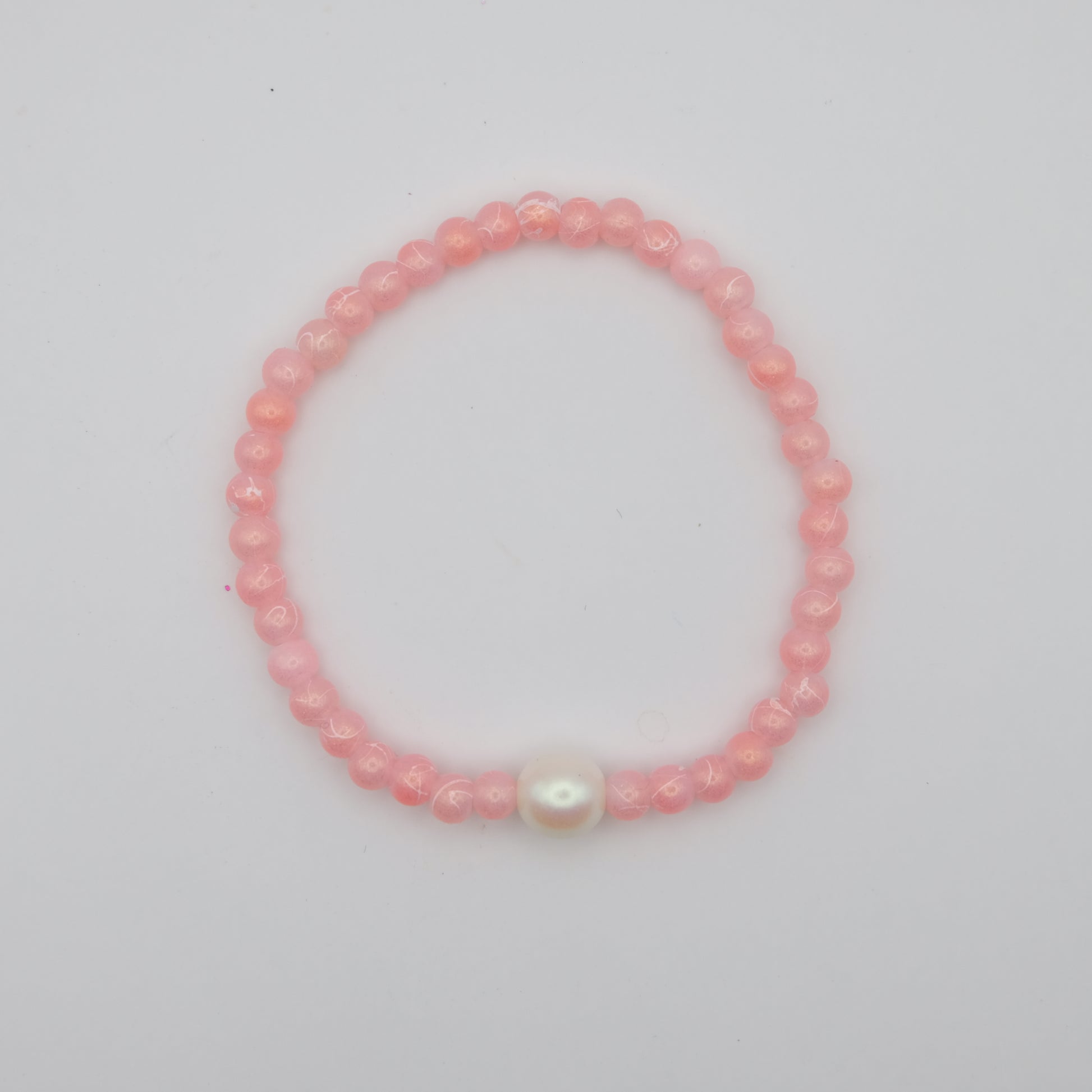 Pink beaded bracelet with a larger Czech glass pearl feature bead on a white background