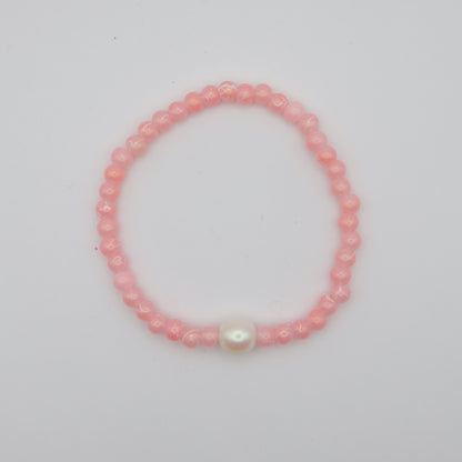 Pink beaded bracelet with a larger Czech glass pearl feature bead on a white background