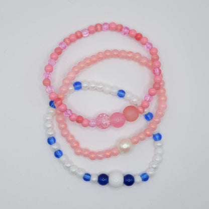 Set of pink, blue, and white beaded bracelets on a light gray background