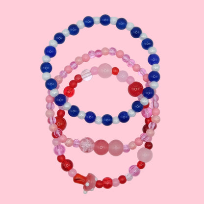 A one of a kind elastic jewellery stack made from mixed glass beads in pink, red and blue tones, designed as a bold layered set.