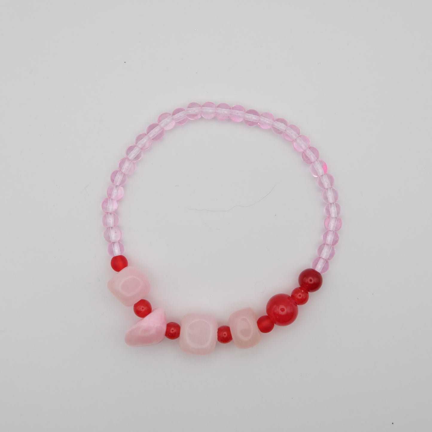 Pink and red beaded bracelet on a light gray background