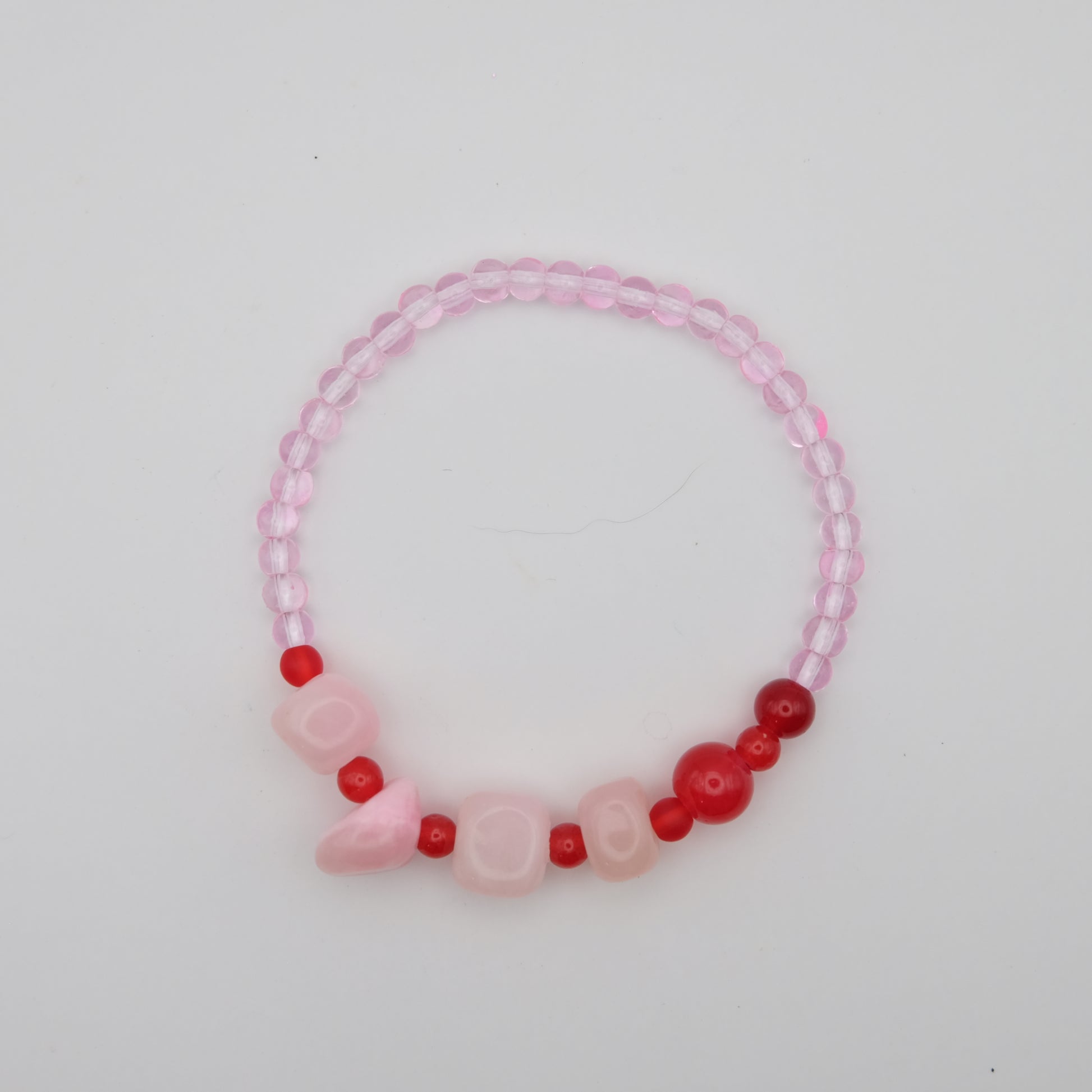 Pink and red beaded bracelet on a light gray background