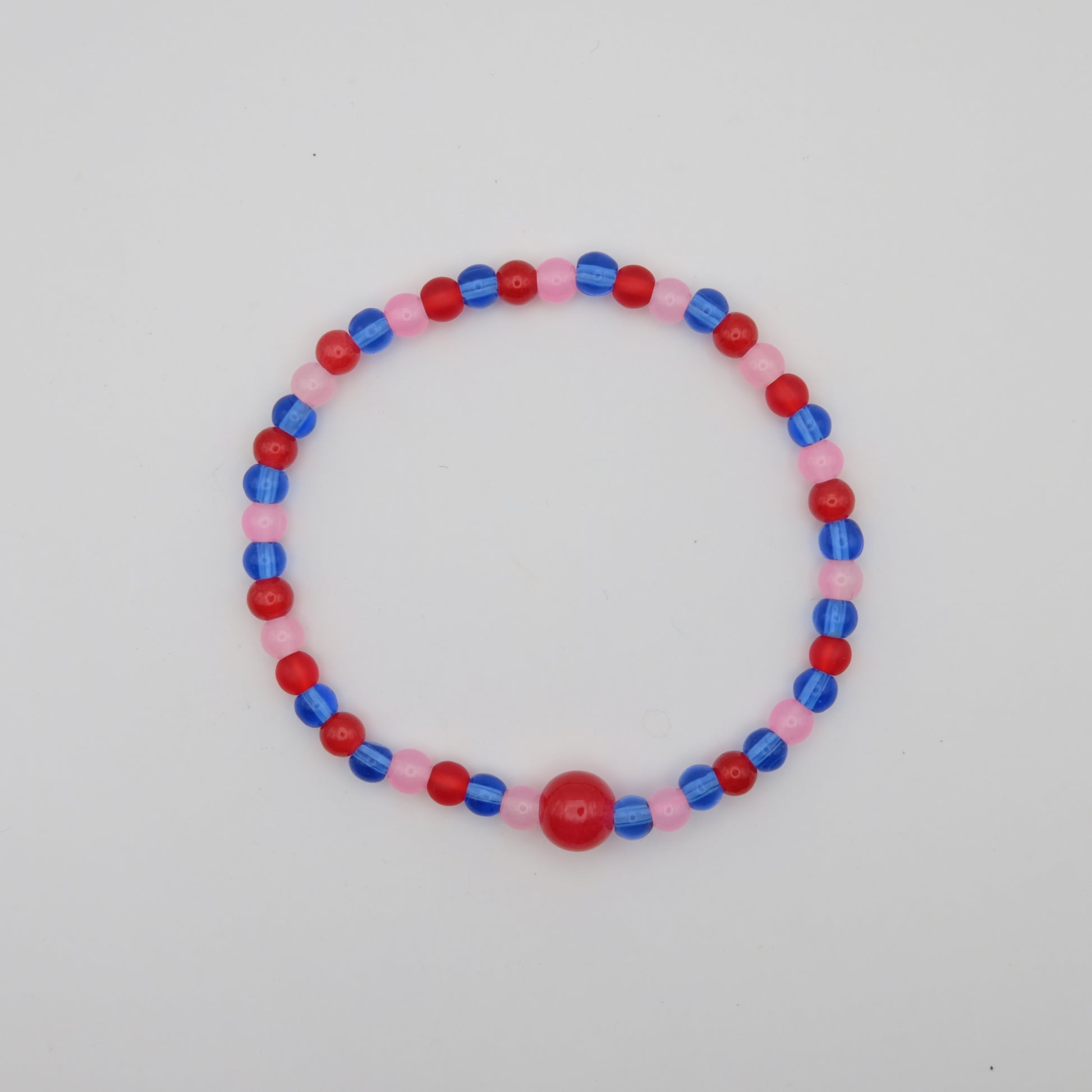 Beaded bracelet with red, blue, and pink beads on a light gray background