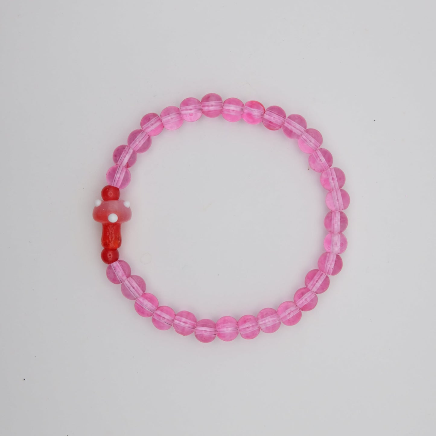 Pink beaded bracelet with a red accent on a white background