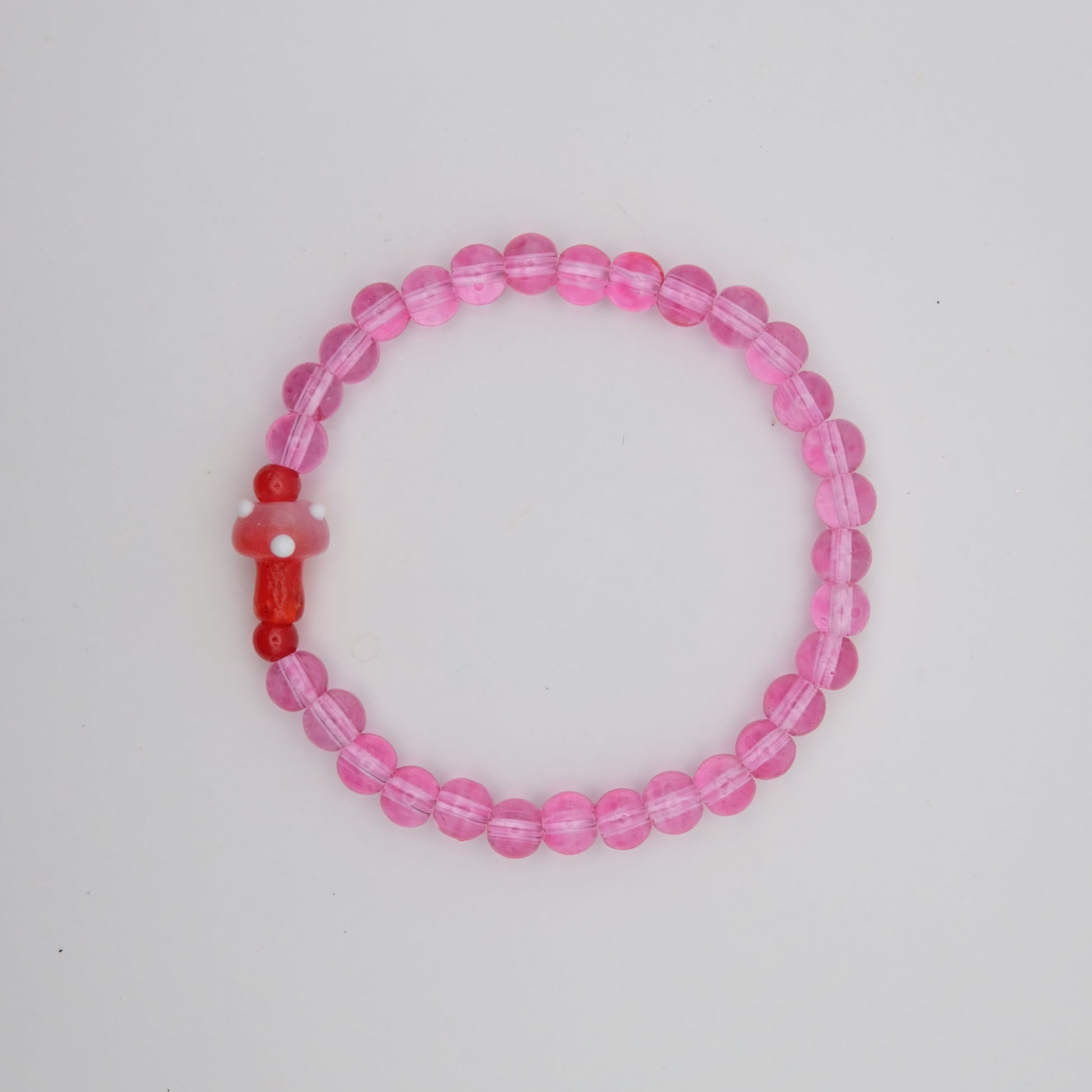 Pink beaded bracelet with a red accent on a white background