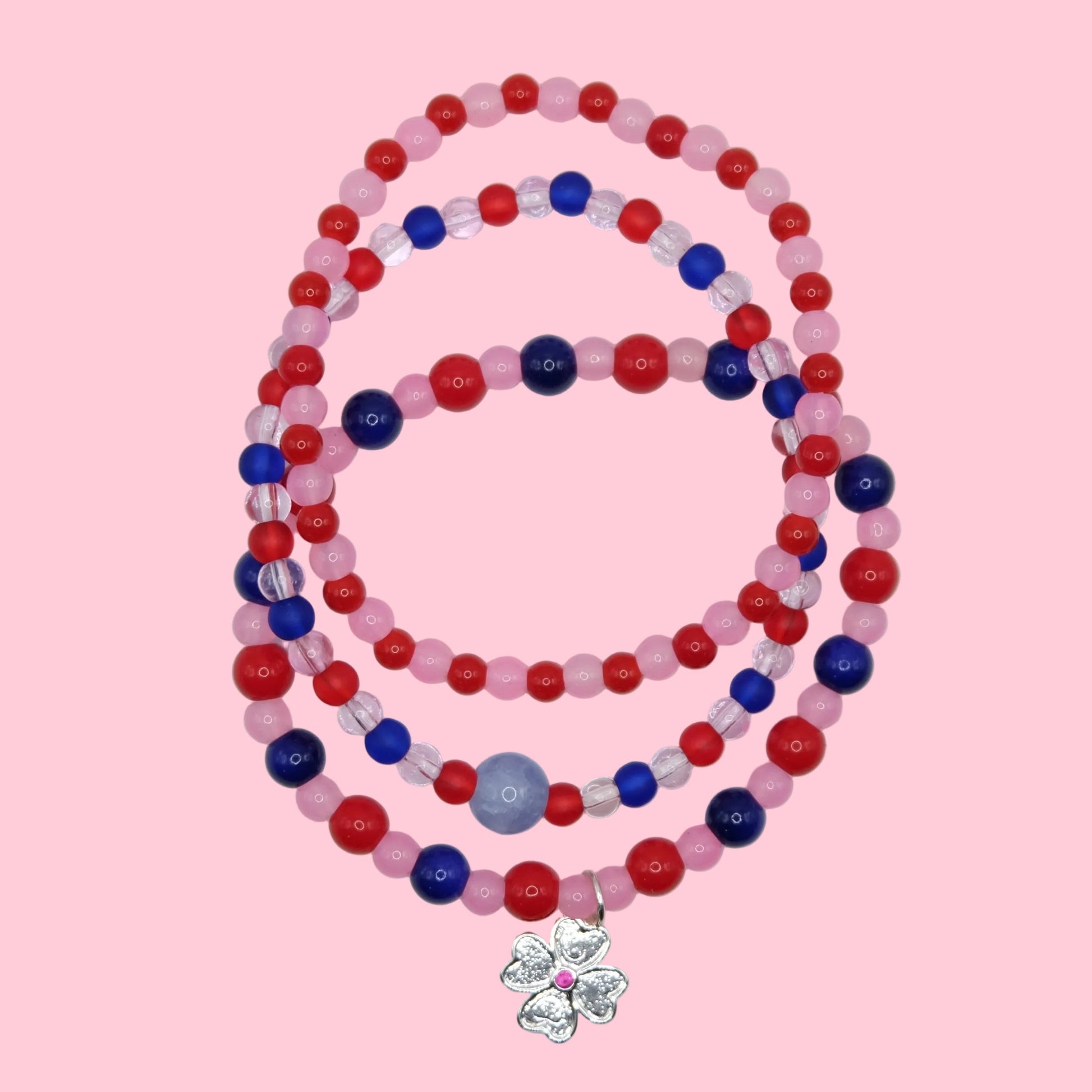 A one of a kind stack of three elastic beaded bracelets featuring colourful glass beads in pink, red and blue with mixed finishes.