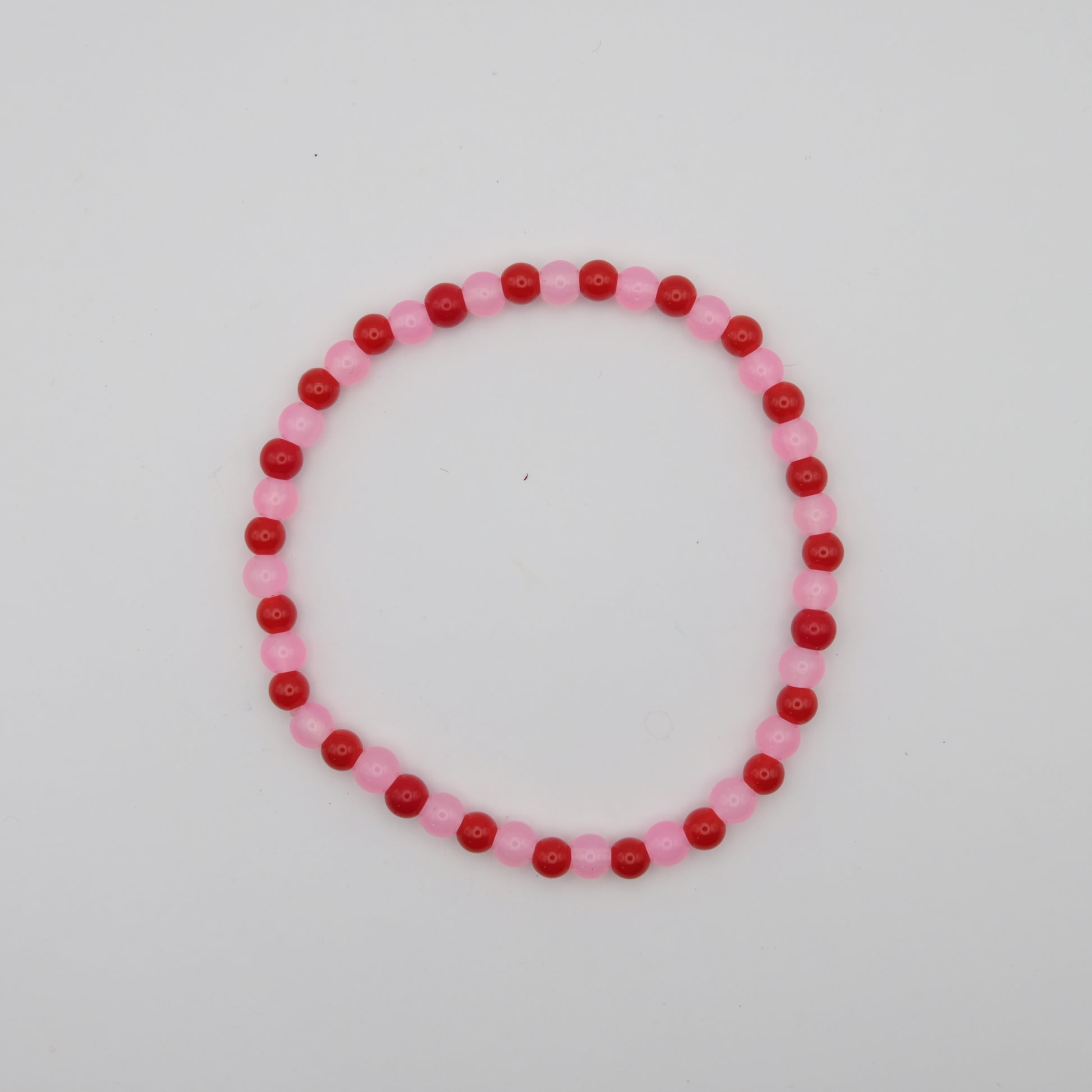 Beaded bracelet with pink and red beads on a white background
