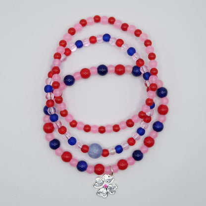 Beaded bracelet stack with red, blue, and pink beads on a plain background