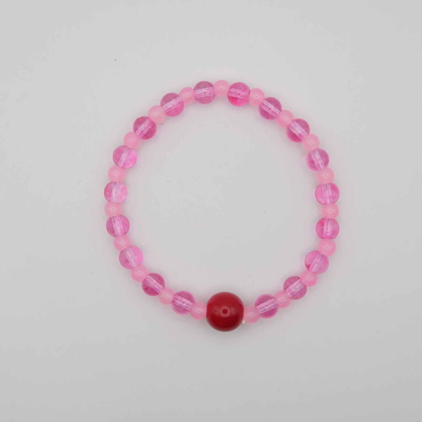 Pink beaded bracelet with a red center bead on a light gray background