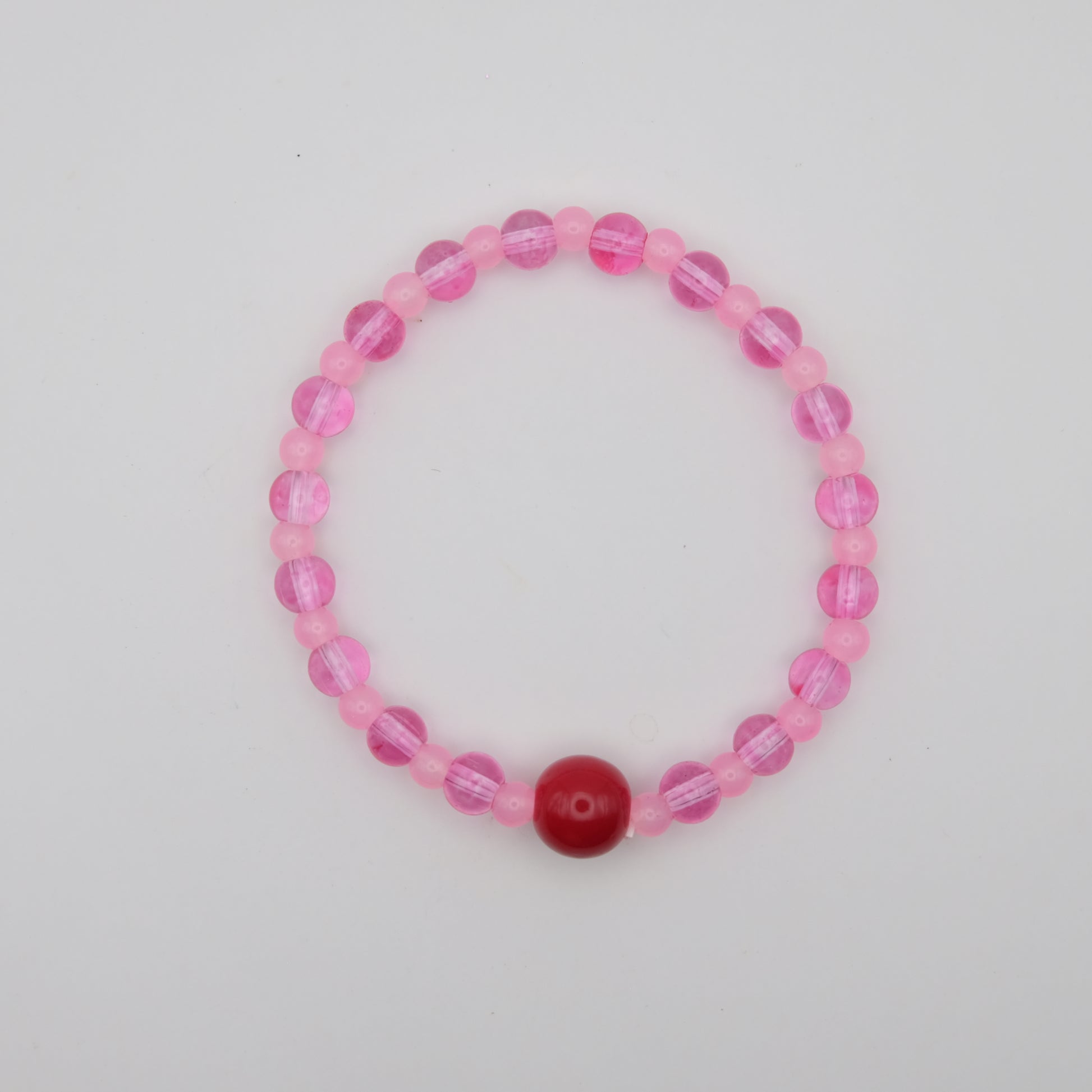 Pink beaded bracelet with a red center bead on a light gray background