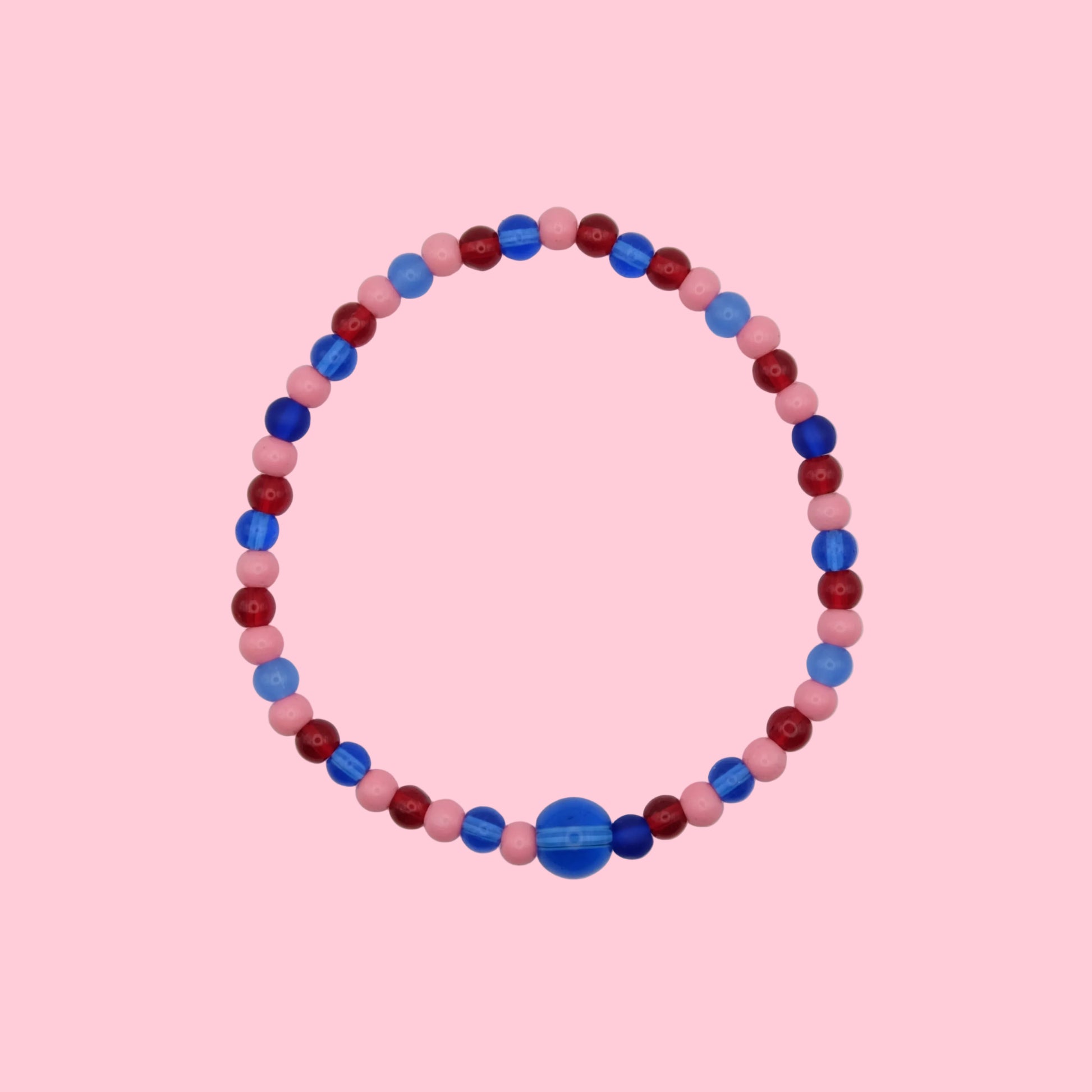 An elastic beaded bracelet composed of 4mm pink, red and blue glass beads - featuring a single 8mm cobalt blue glass bead, shown on a white background.