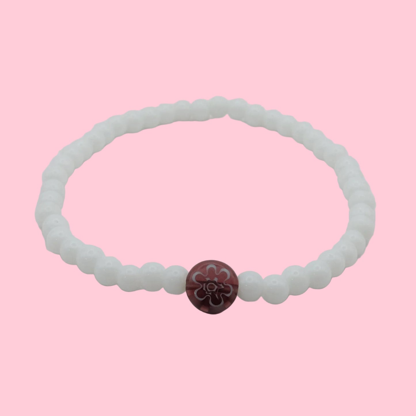 An elastic beaded bracelet composed of glossy white 4mm glass beads featuring a single plum floral lampwork bead at the centre, shown on a white background.