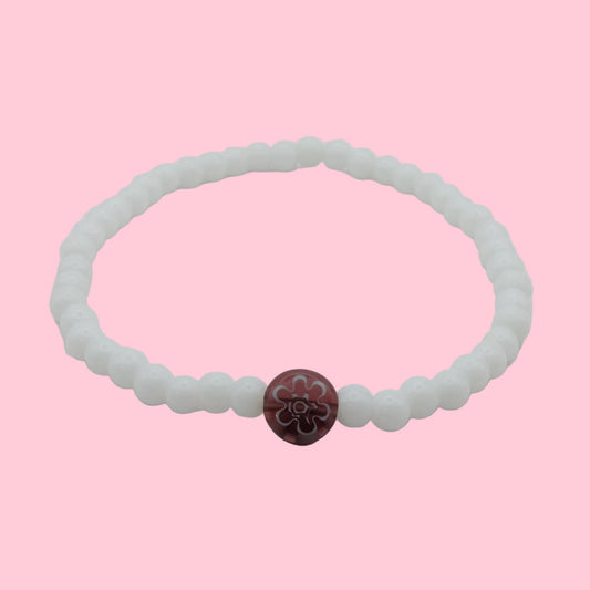 An elastic beaded bracelet composed of glossy white 4mm glass beads featuring a single plum floral lampwork bead at the centre, shown on a white background.