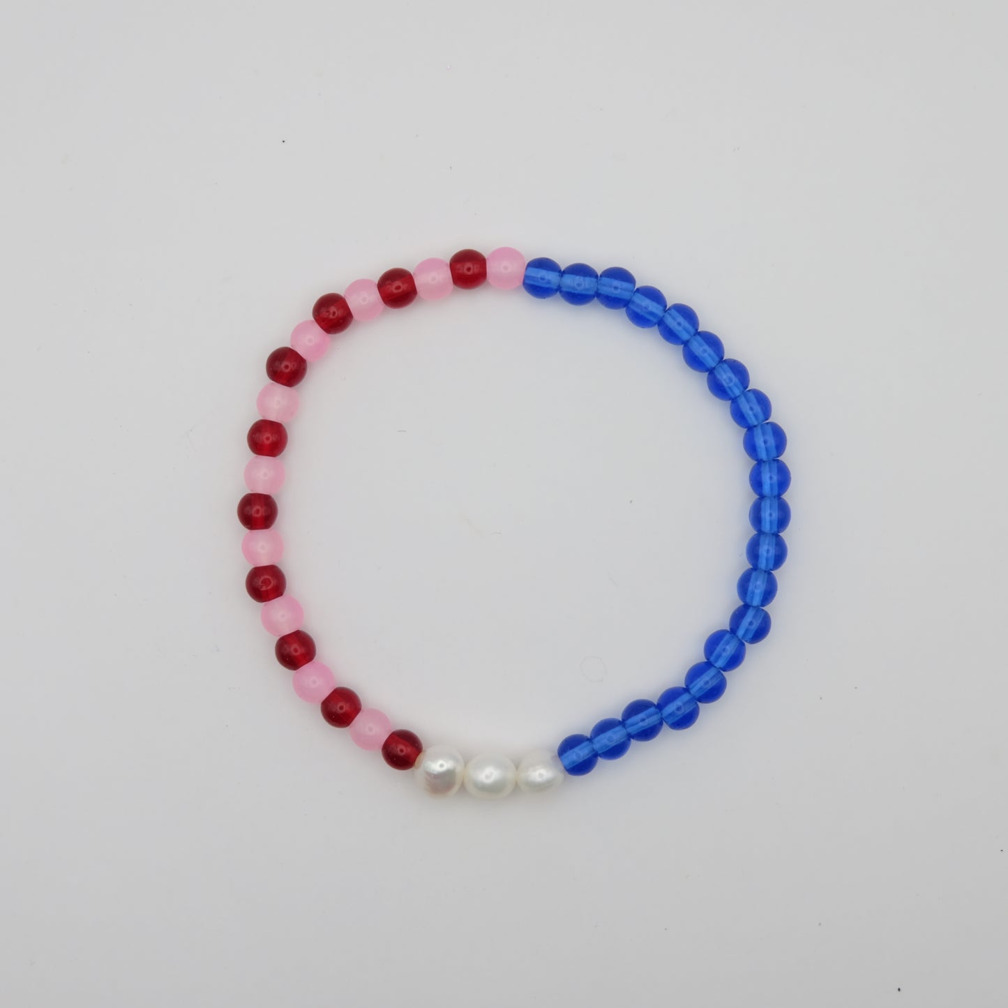 Beaded bracelet with red, pink, and blue beads on a white background