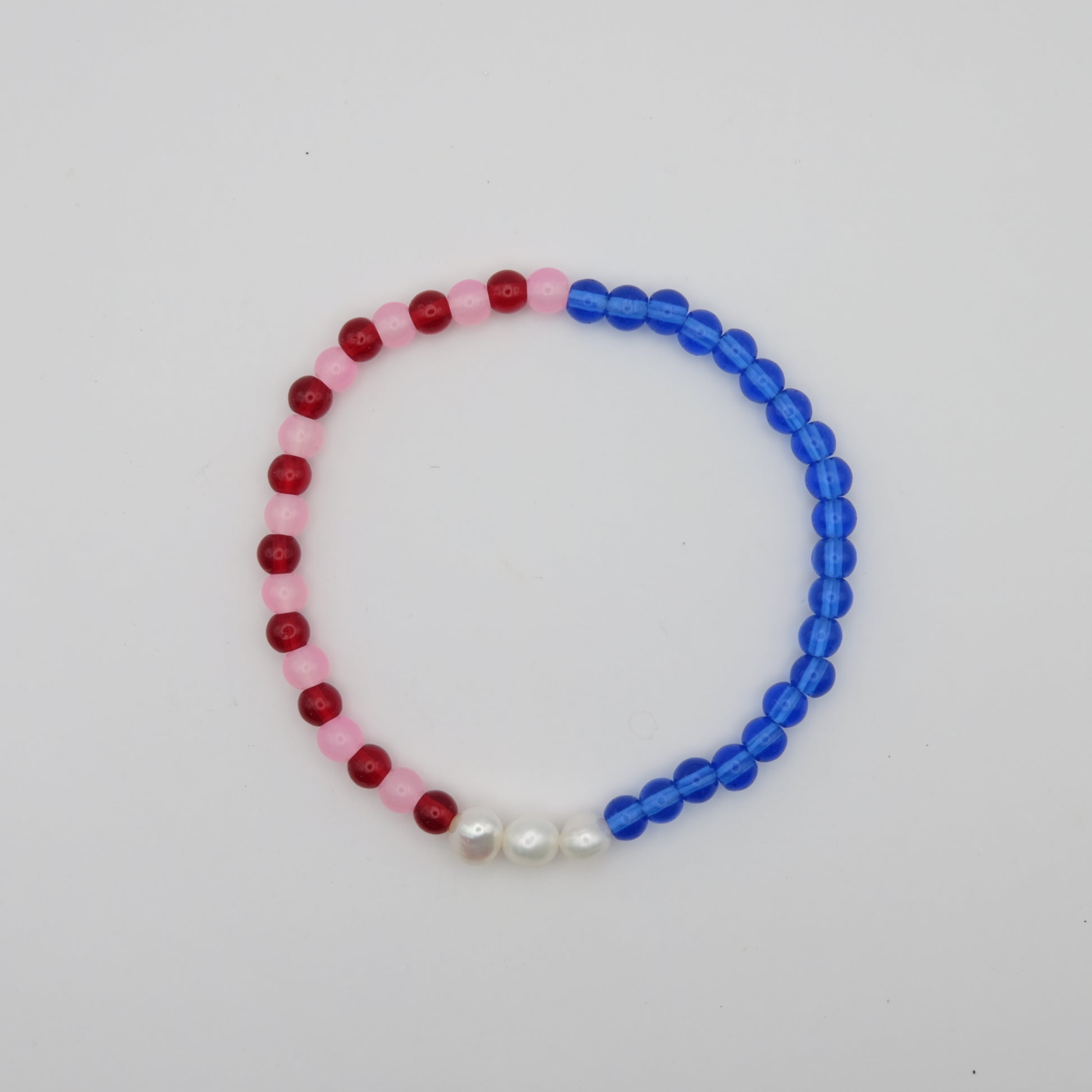 Beaded bracelet with red, pink, and blue beads on a white background