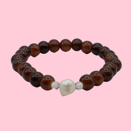 An elastic beaded bracelet composed of 6mm translucent cocoa and chestnut brown glass beads, featuring a freshwater pearl focal bead framed by clear accent beads, shown on a clean white background.