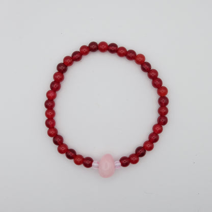 Beaded bracelet with red beads and a pink bead on a white background