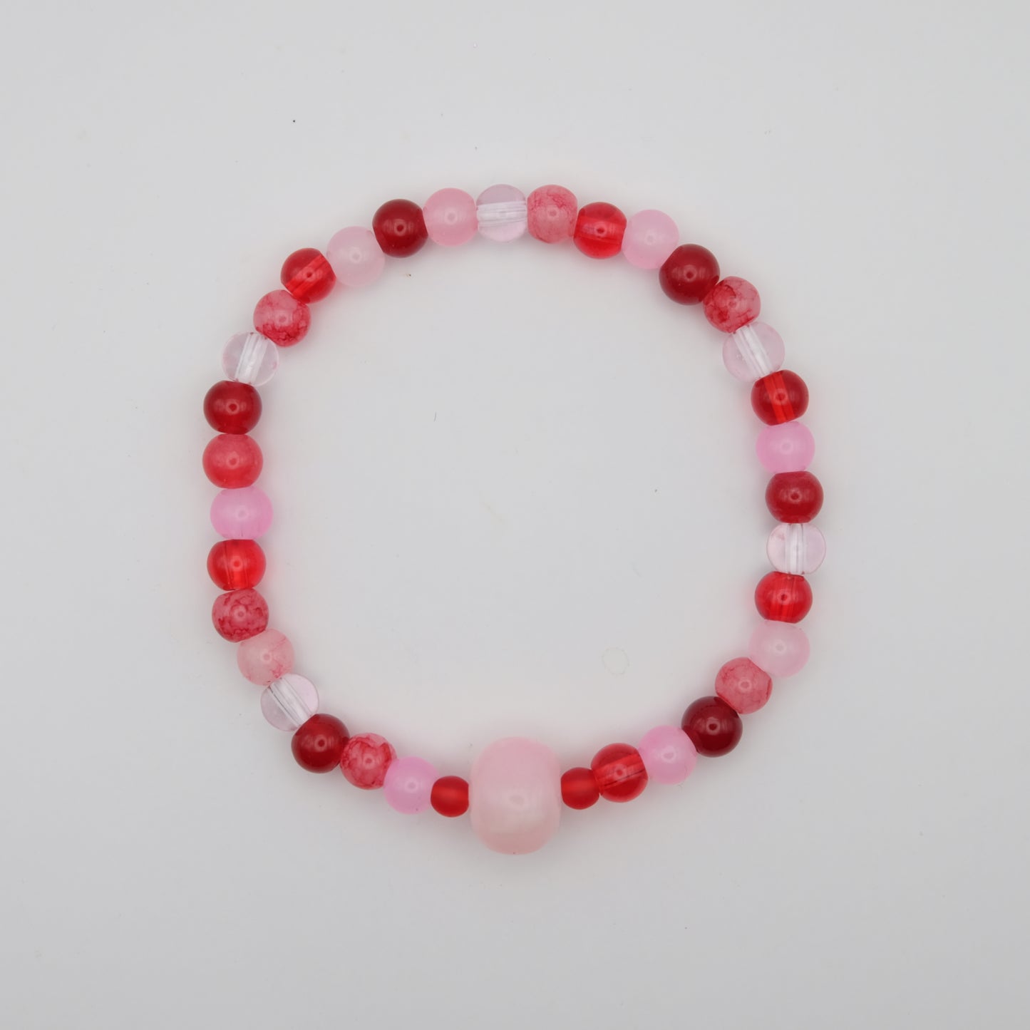 Beaded bracelet with red and pink beads on a light gray background