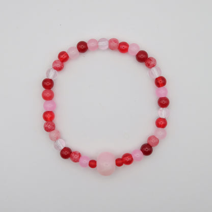 Beaded bracelet with red and pink beads on a light gray background