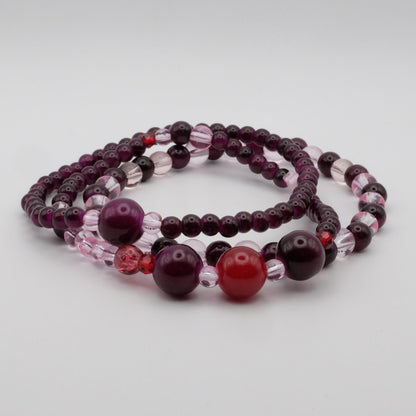 Set of beaded bracelets with purple and red beads on a light gray background