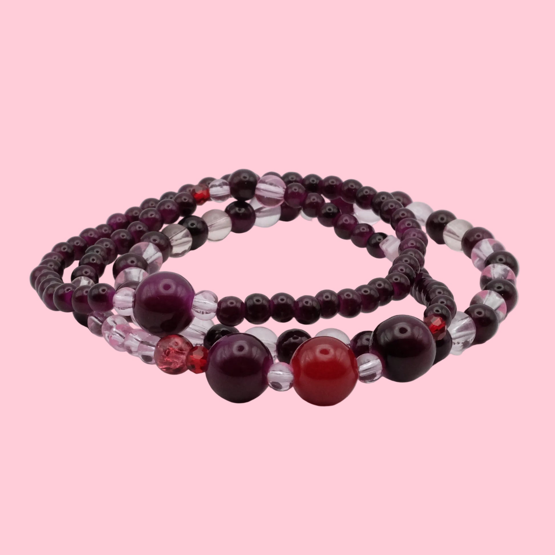 Layered bracelet stack featuring plum glass beads, burgundy focal beads, crystal accents and rich berry tones.