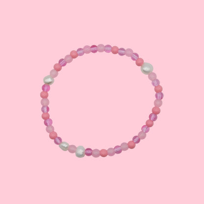 An elastic beaded bracelet composed of 4mm glass beads in pink  tones - featuring small freshwater pearl accents, shown on a white background.