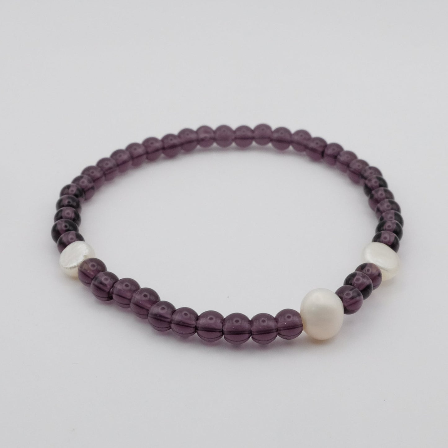 Beaded bracelet with purple and white beads on a light gray background