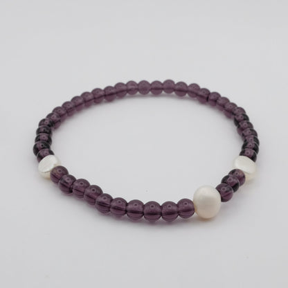 Beaded bracelet with purple and white beads on a light gray background